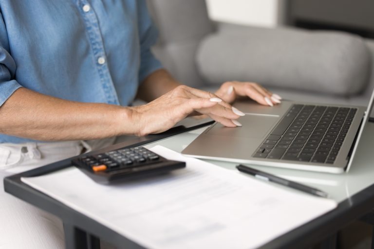 Woman,Using,Laptop,Sit,At,Desk,,Calculator,And,Document,Nearby,